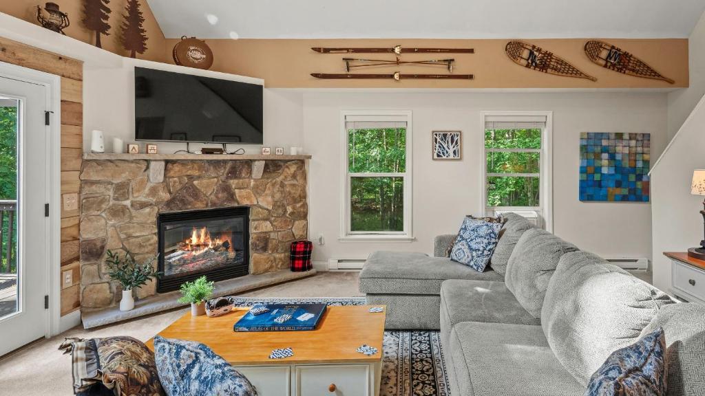 Alpine Serenity by AvantStay Beach Lake Access Theater Deck Playroom في Albrightsville: غرفة معيشة مع أريكة ومدفأة