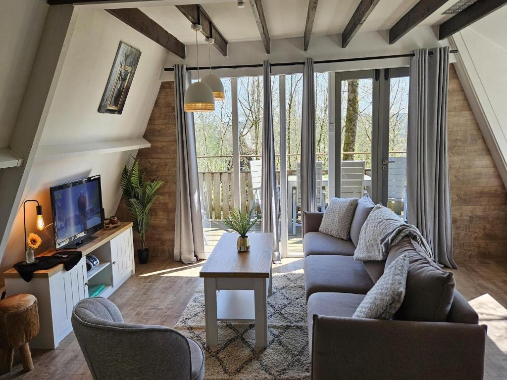 Una sala de estar con un sofá y un televisor. en Peaceful Forest Chalet near Durbuy, en Septon