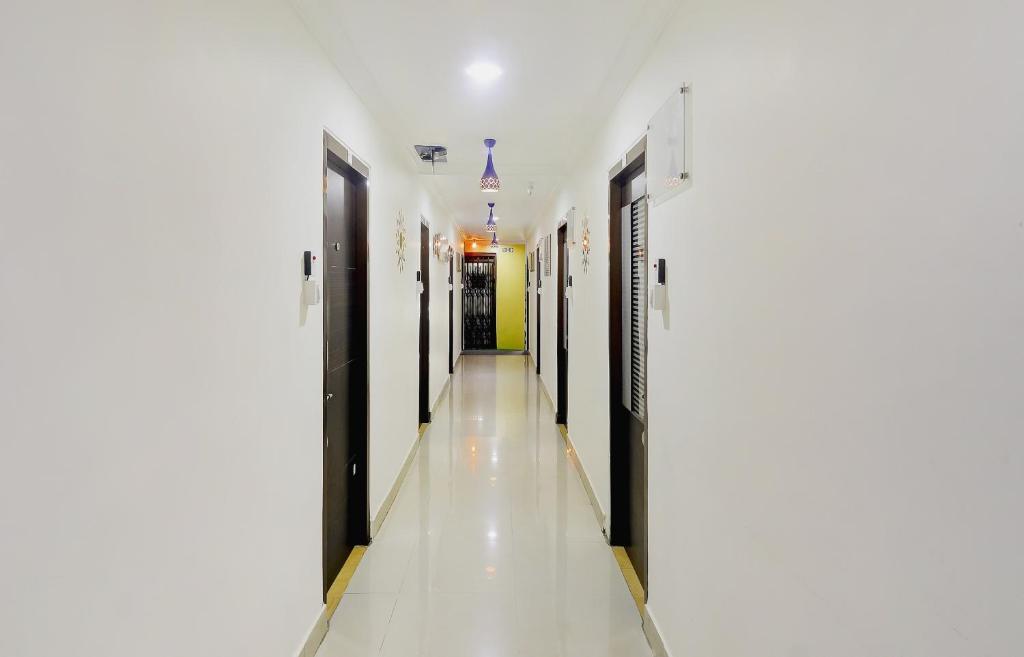 Un pasillo de un hospital con puertas negras y suelos blancos. en OYO 76333 Newgen Grand, en Hyderabad