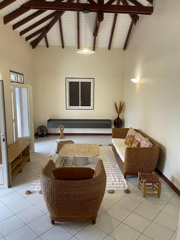 a living room with wicker chairs and a couch at Villa Jakéna à Sainte-Rose in Sainte-Rose