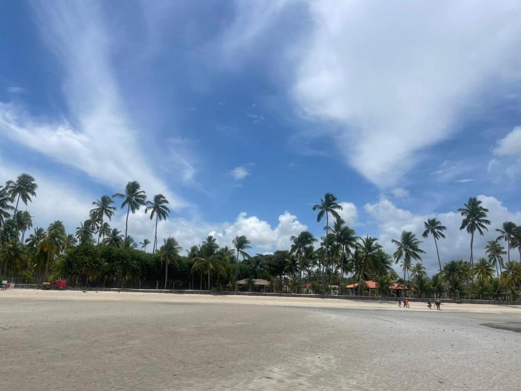 een leeg strand met palmbomen en een bewolkte lucht bij Max Suites block A, apartment 002 in Praia dos Carneiros
