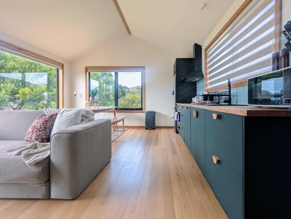 Sisters Beach Hideaway - A Coastal Escape في Sisters Beach: غرفة معيشة مع أريكة ومطبخ