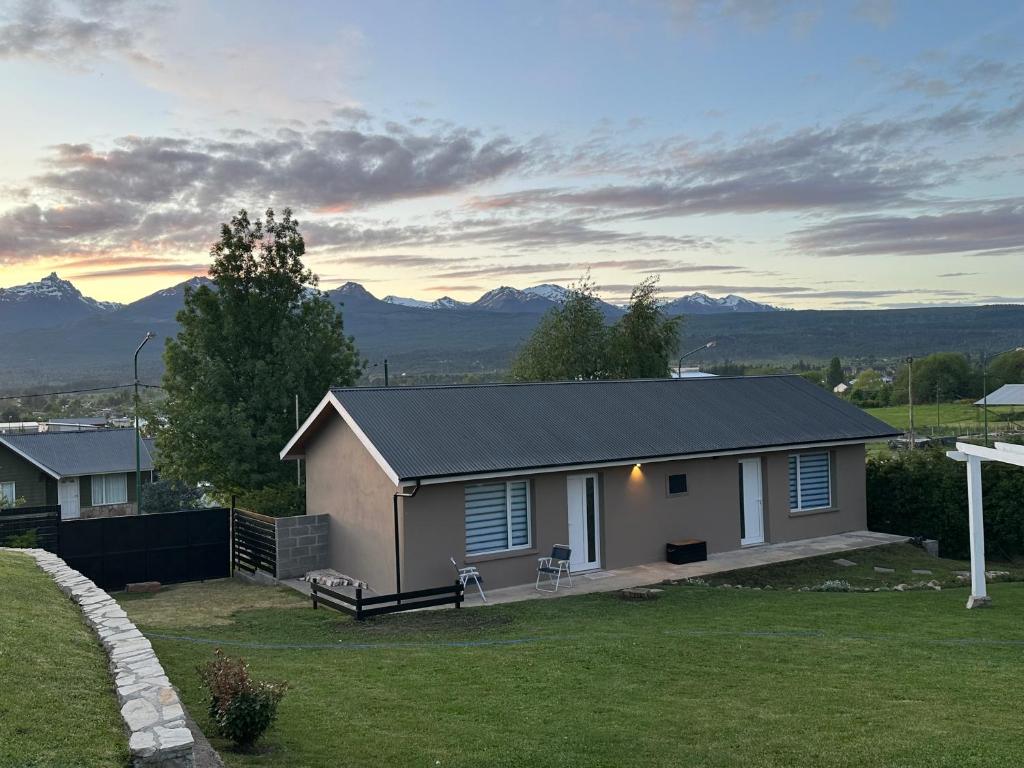 uma pequena casa branca com montanhas ao fundo em Patagonia Nido em Trevelín