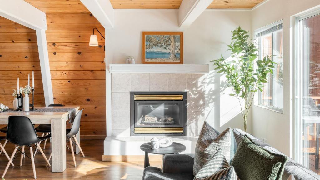 ein Wohnzimmer mit Kamin, Tisch und Stühlen in der Unterkunft Chickaree by AvantStay A-Frame w Mountain Views in Tahoe City