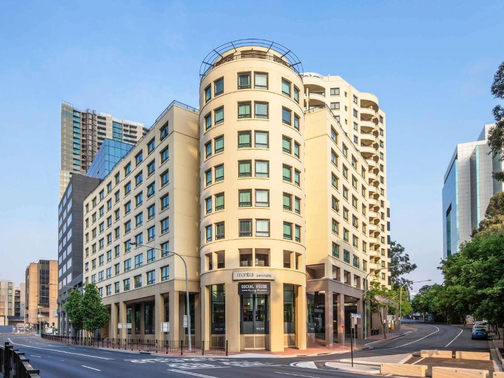a tall tan building on a city street at Mantra Parramatta in Sydney