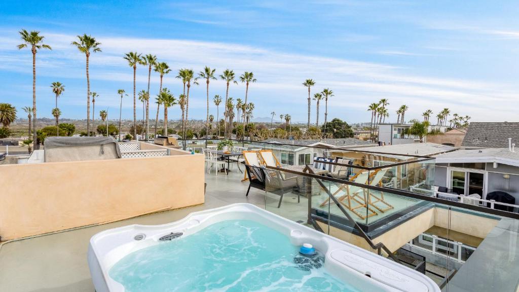 Velvet Sand I by AvantStay Steps to Newport Beach Private Rooftop w Outdoor Kitchen Hot Tub في شاطئ نيوبورت: حوض استحمام ساخن على شرفة مع أشجار النخيل