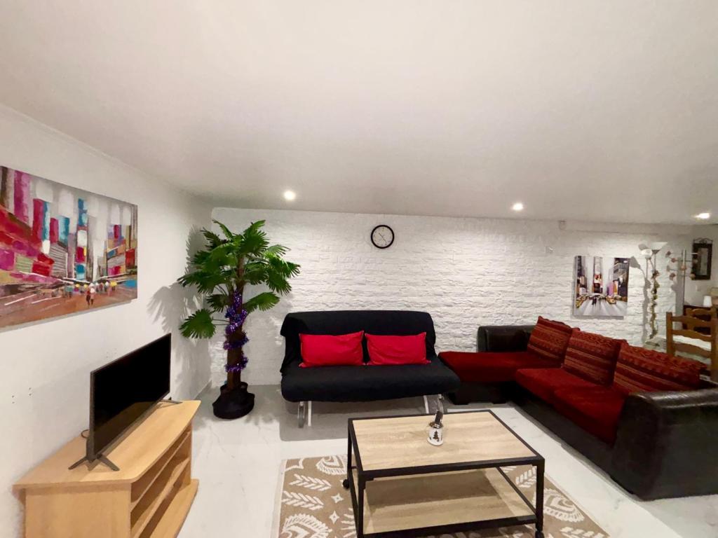 soggiorno con divano nero e cuscini rossi di confortable et spacieux 80m2 a Bailly-Romainvilliers