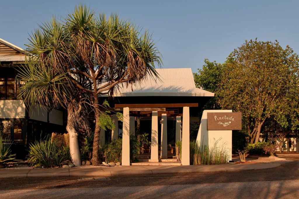 a building with a palm tree in front of it at Pinctada Hotel Broome in Broome