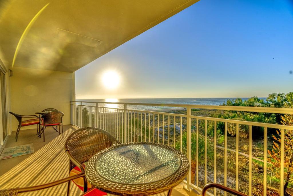 een balkon met een tafel en stoelen en de oceaan bij Madeira Norte Beachfront Condo - Walk To John's Pass in St Pete Beach