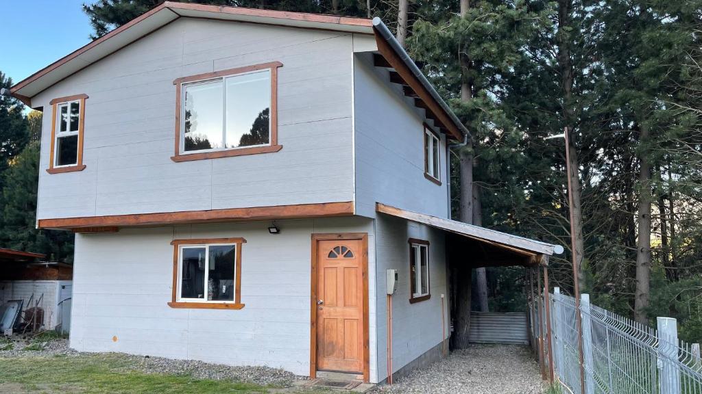 Casa blanca pequeña con puerta y ventanas en Cabaña la percha II, en Coyhaique