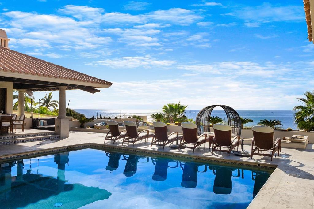 a pool with chairs and the ocean in the background at Casa Brooks in Cabo San Lucas