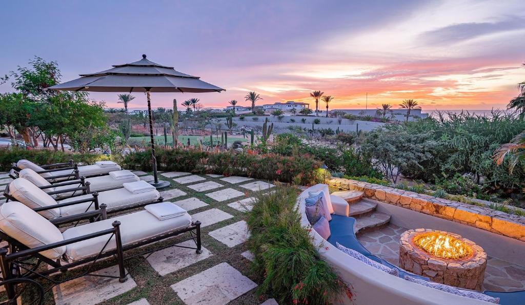 um pátio com cadeiras, um guarda-sol e uma fogueira em Palmaritos 6 em El Tule