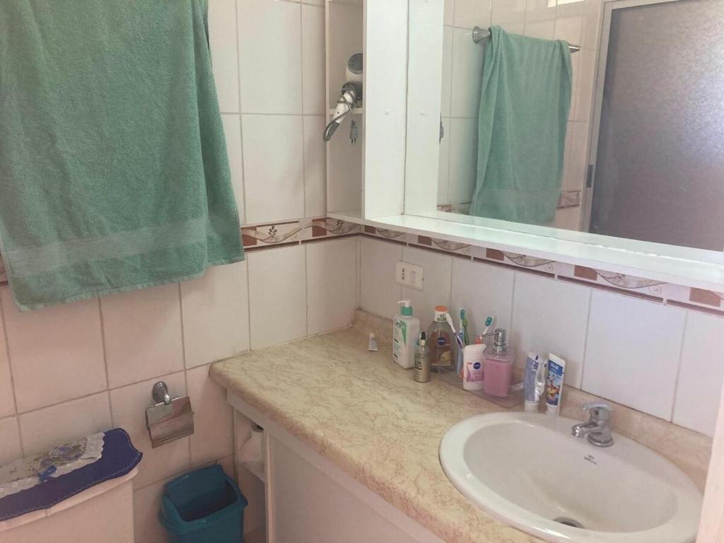 Departamento frente al mar في تومي: حمام مع حوض ومرآة ومنشفة خضراء