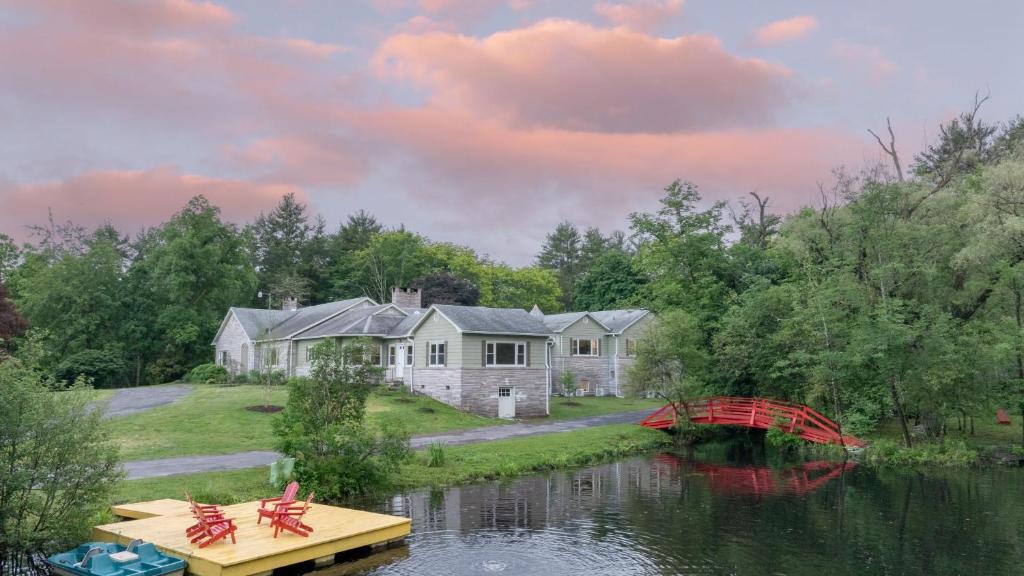 a house on the water with a bridge and a house at Game Farm Villa by AvantStay 10BDR Private Pond Spa Pool Family-Friendly in Catskill