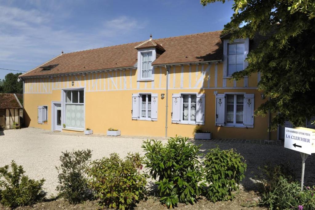 a yellow house with white windows and a driveway at LA CLER'HIER in Clérey