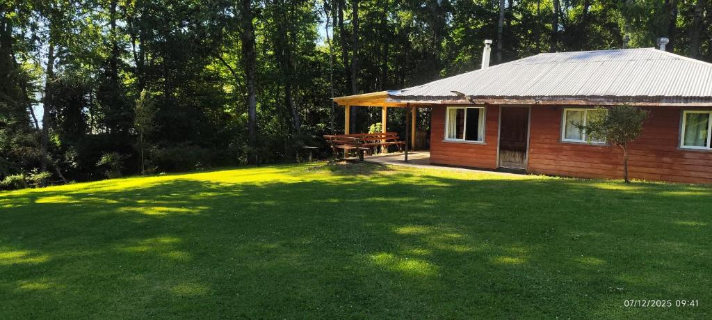a small cabin in a yard with a large lawn at Cabaña Leandro Lago Panguipulli in Panguipulli