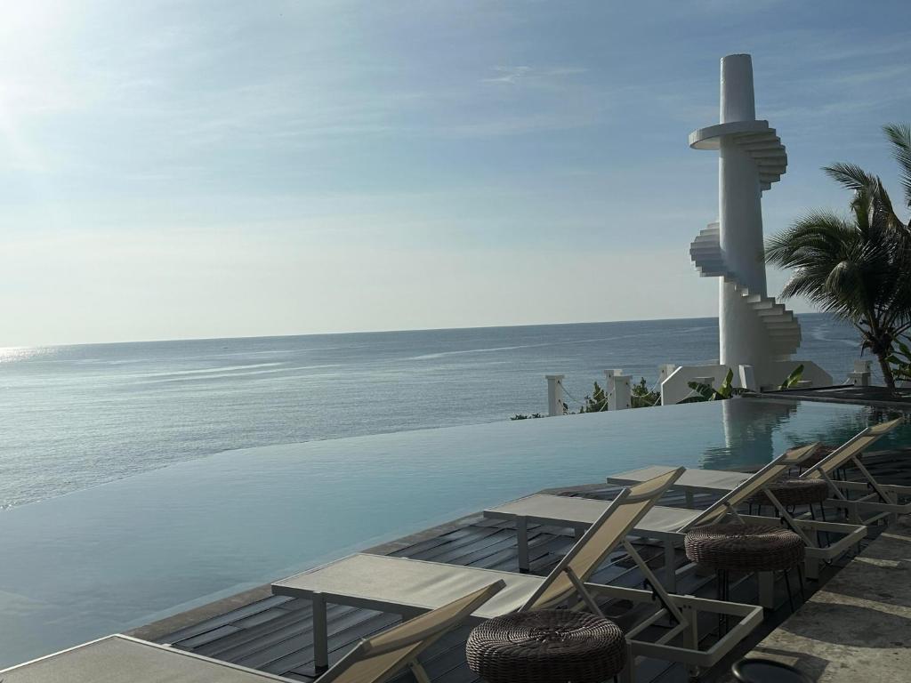 Una piscina con sillas y el océano. en Trogon's Perch, en San Isidro