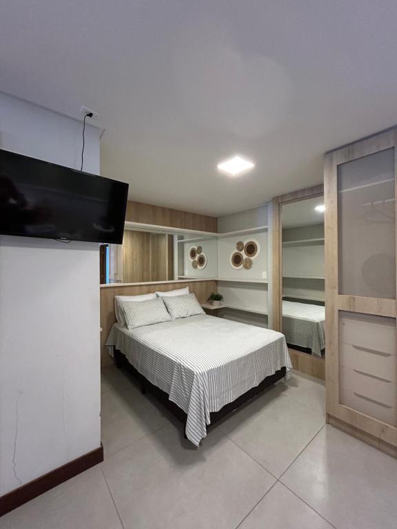 a bedroom with a bed and a flat screen tv at Residence Farol - Loft 213 - Vista mar Prainha e Farol in Laguna