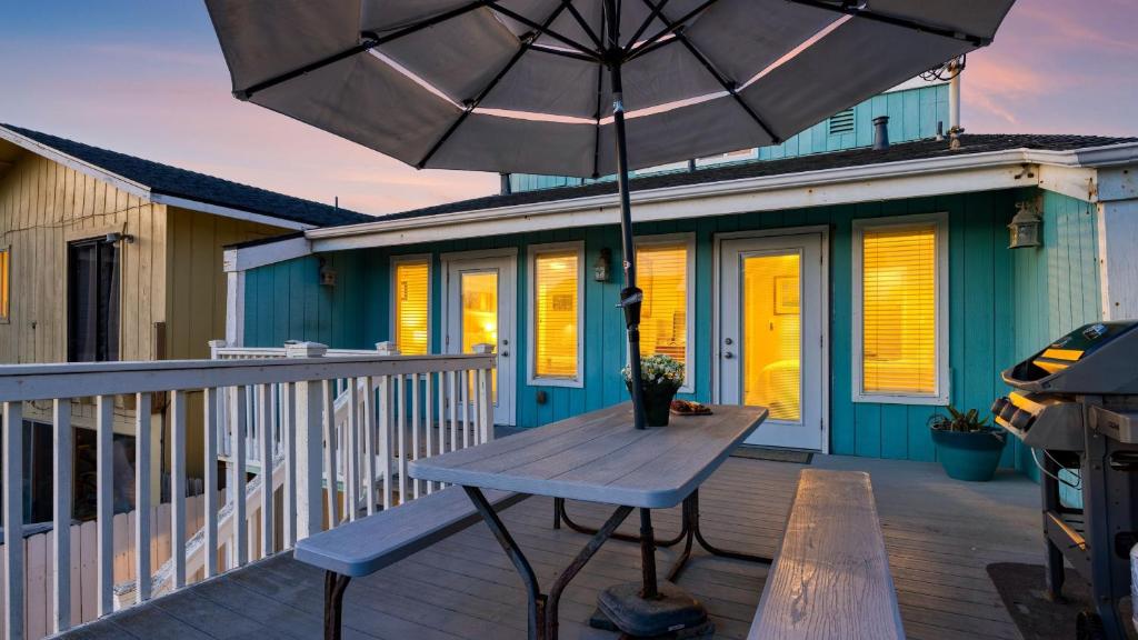 a wooden table with an umbrella on a deck at Steps to Beach w PatioDeck Foosball Happy Bottom Beach House by AvantStay in Oceano