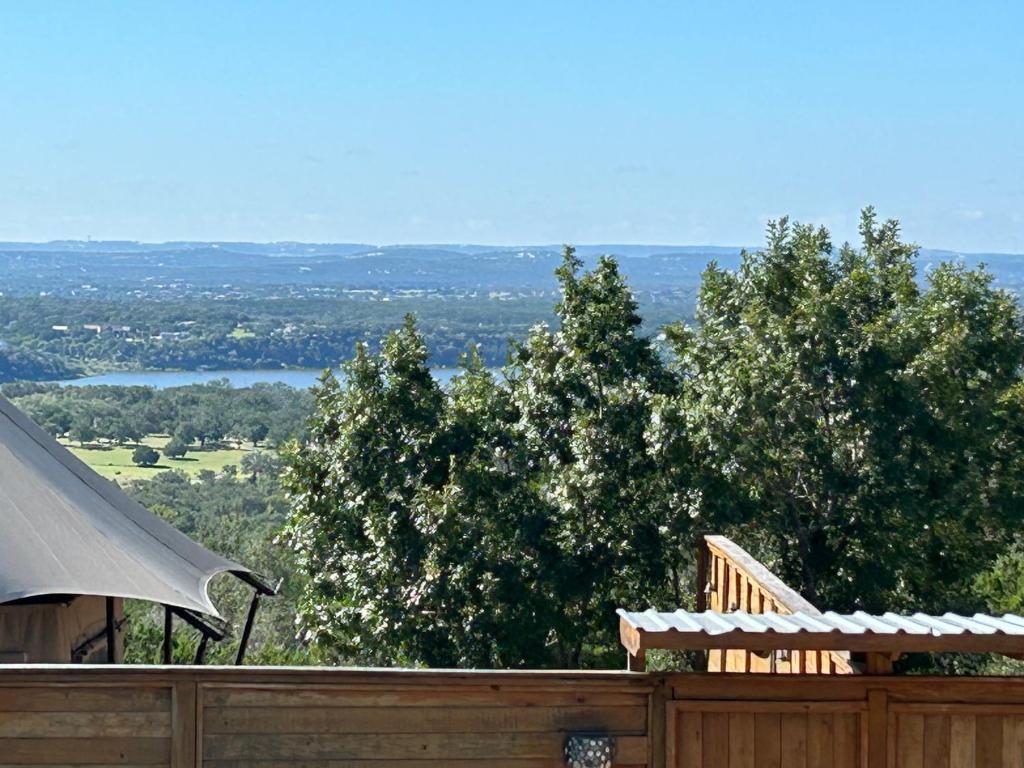 een houten schutting met uitzicht op bomen en een meer bij Premium Suite 1-Safari Tent-Private Hot Tub in Marble Falls