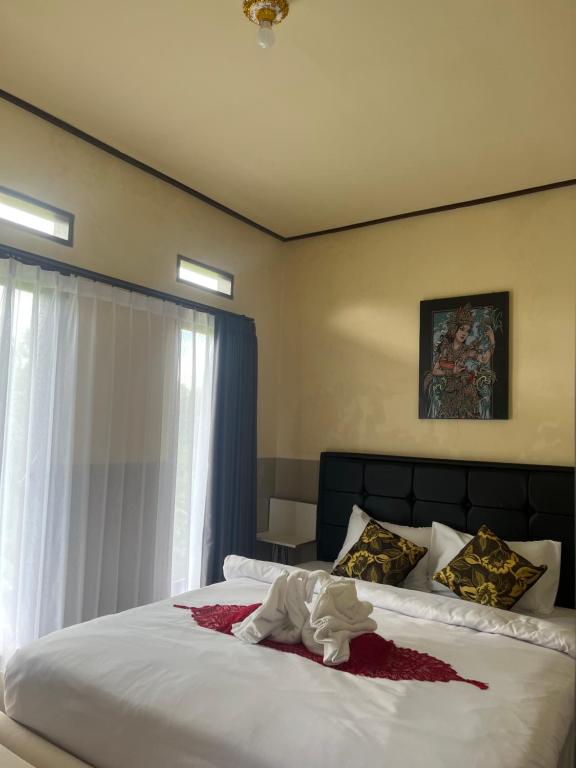 ein Schlafzimmer mit einem großen weißen Bett mit einem Fenster in der Unterkunft Wayan Bola Homestay in Sidemen