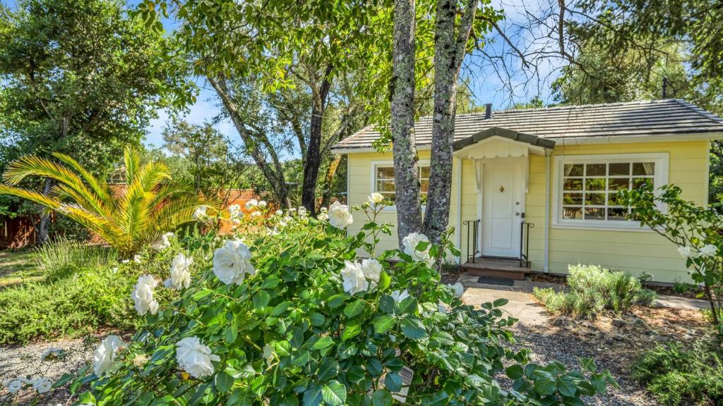 un cottage jaune avec des fleurs blanches devant dans l'établissement Grapevine Cottage by AvantStay Hobby Vineyard Firepit, à Glen Ellen