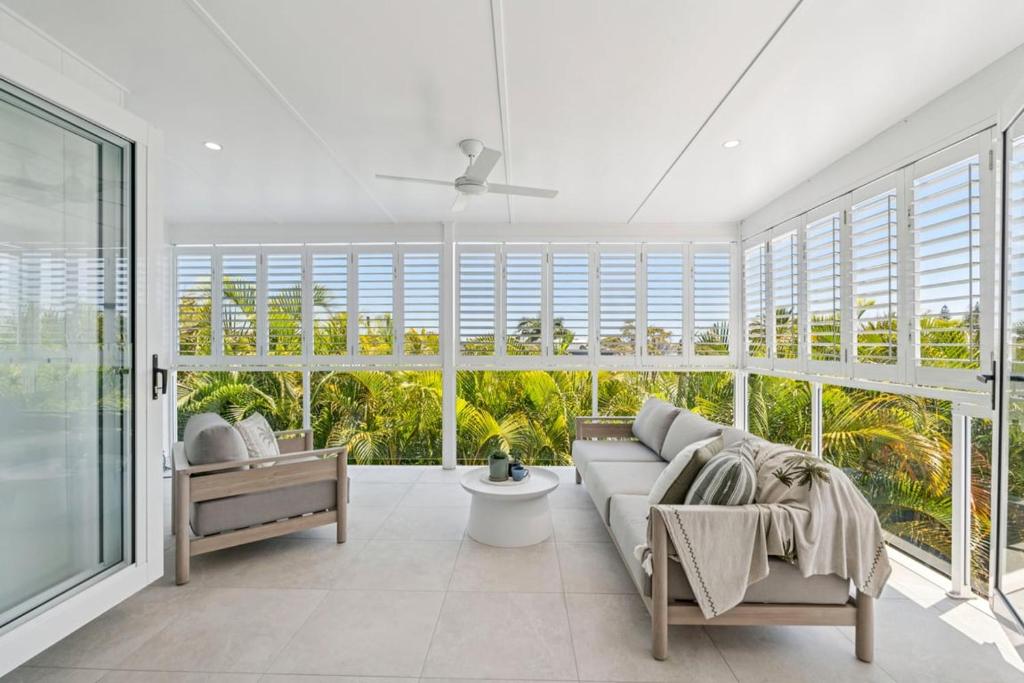 a living room with a couch and large windows at The Cheeky Palm - Beachy, enjoy a cheeky cocktail! in Woolgoolga