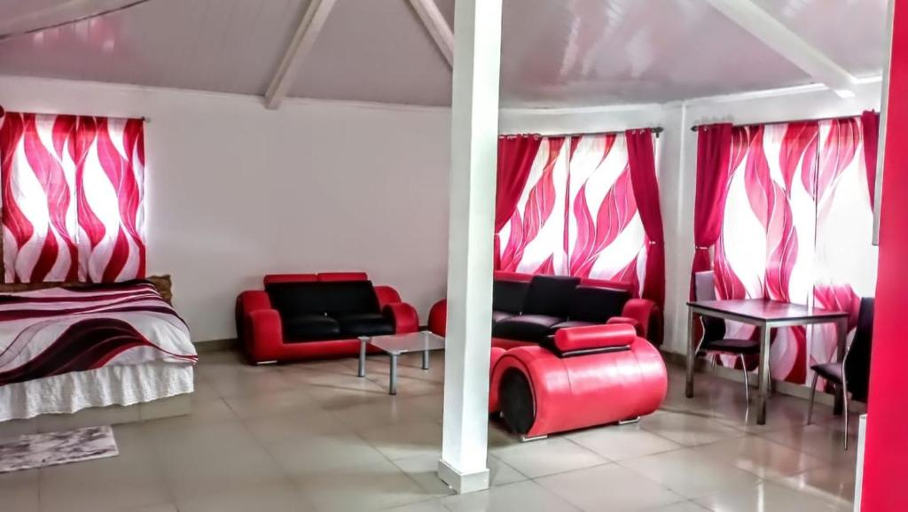 a room with red chairs and a bed and a table at Ecotropicfarmhouse in Cerro Azul