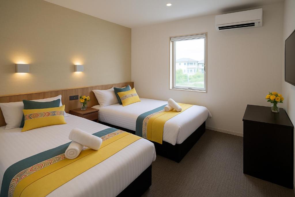 een hotelkamer met twee bedden en een televisie bij Plaza In Kanku Hotel in Izumi-Sano