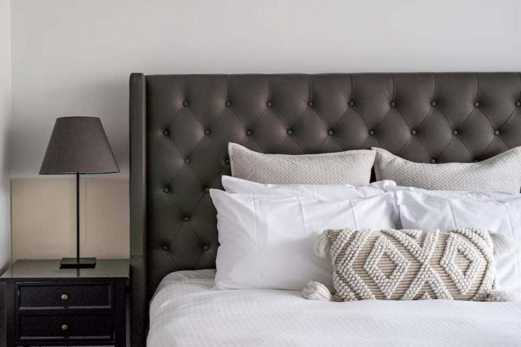a bed with white pillows and a lamp on a night stand at Bay View Breeze in Lorne