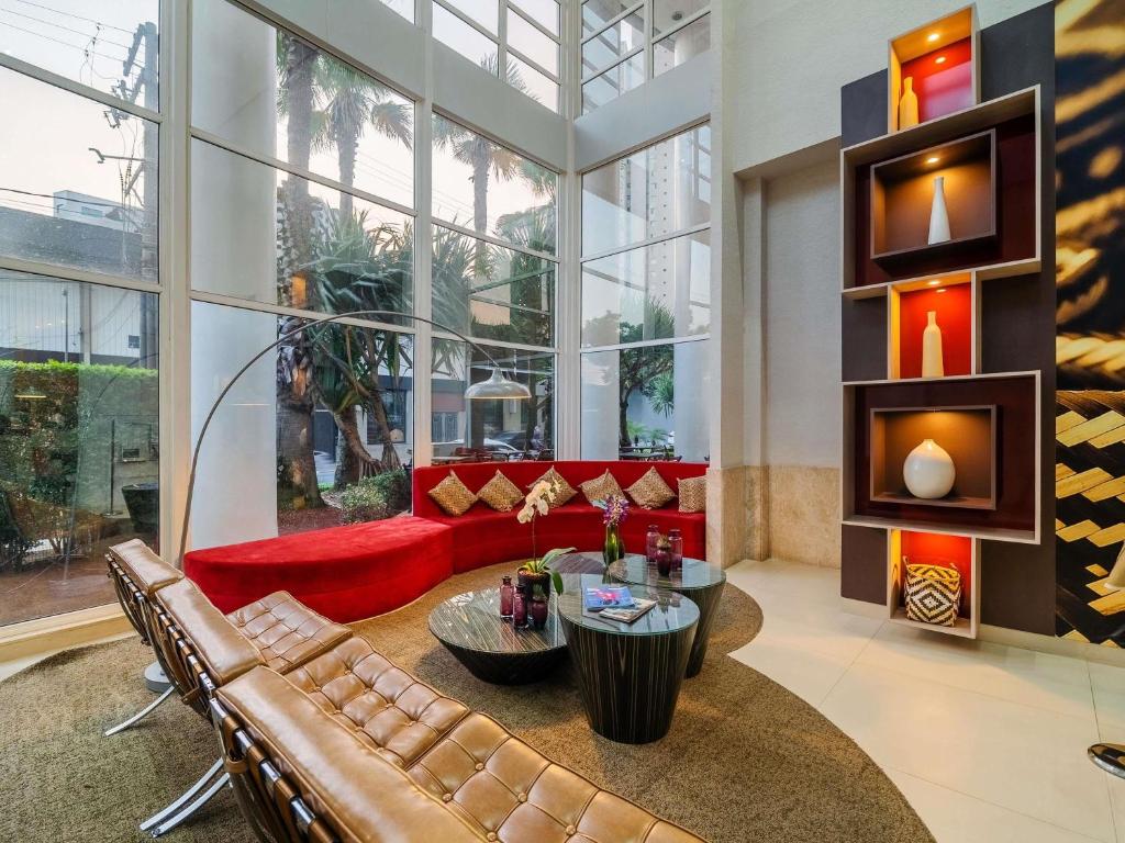 a living room with a red couch and a fireplace at Mercure Guarulhos Aeroporto in Guarulhos