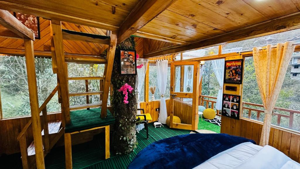 a bedroom with a bed in a room with windows at Bawli Treehouse Duplex, Jibhi in Jibhi