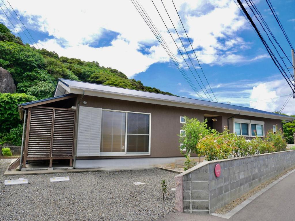a house with a hill in the background at Lulumalu AMAMI in Amami