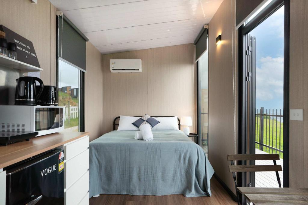 a small bedroom with a bed and a microwave at Aorangi Peak Cabins 1 by Tiny Away in Rotorua