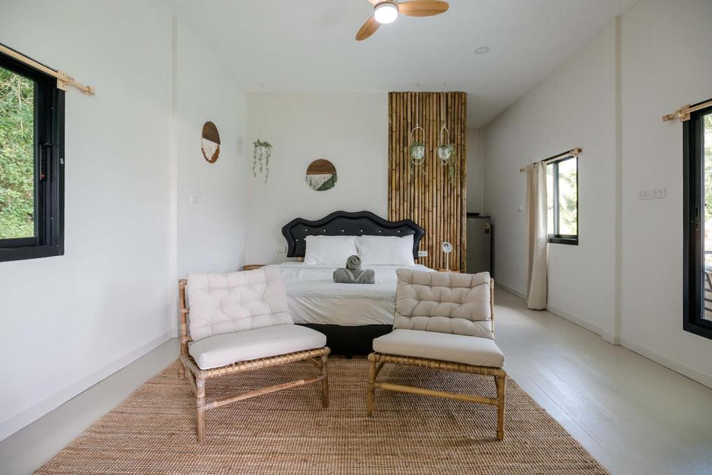ein Schlafzimmer mit einem Bett und zwei Stühlen in der Unterkunft Cozy Seaview Studio 50 Meters From the Beach in Ko Kong Nui