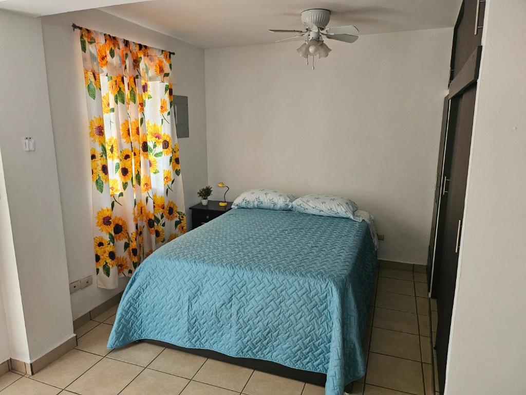a bedroom with a bed with a blue comforter at El hostal de Uriel in Izalco