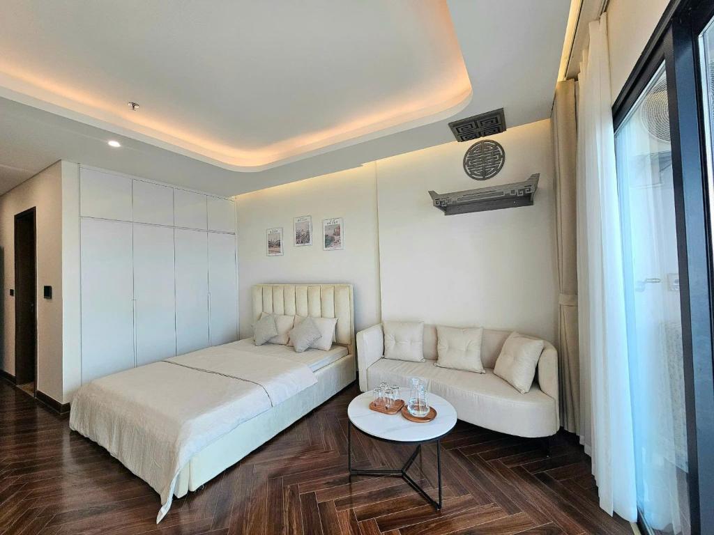 Căn hộ homestay Doji Diamond Crown في هاي فونج: غرفة نوم بها سرير وأريكة وطاولة