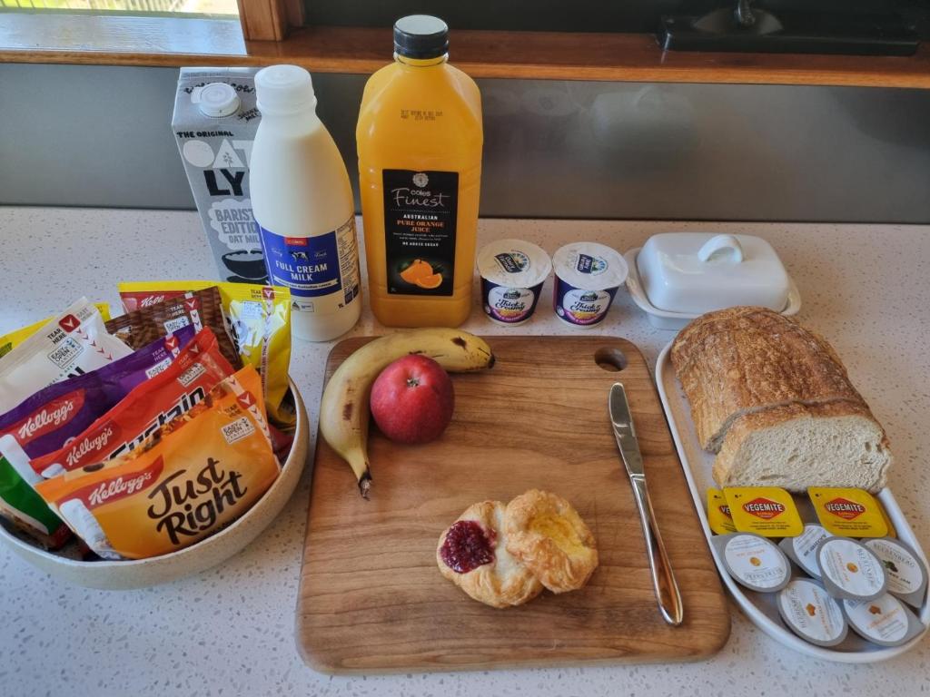 Kookaburra Retreat - Apartment في بكنهام: طاولة مع لوح تقطيع للطعام والخبز والحليب