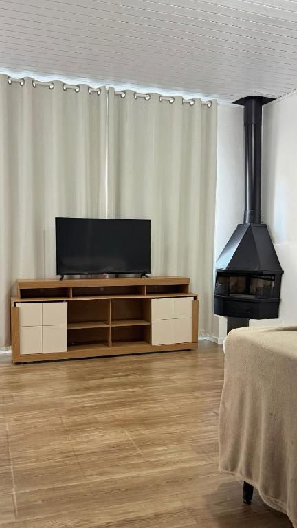 a living room with a television and a stove at Flat aconchegante a 500m do centro de Chapecó in Chapecó