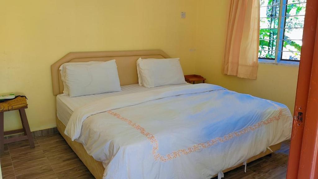 Teratak Jannah Homestay & Resort في كوالا لكانغسار: سرير به وسادتان في غرفة النوم