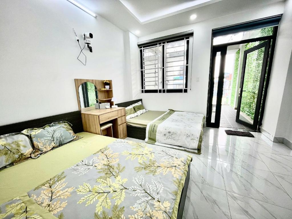 a bedroom with two beds and a desk and windows at AP Home in Ho Chi Minh City