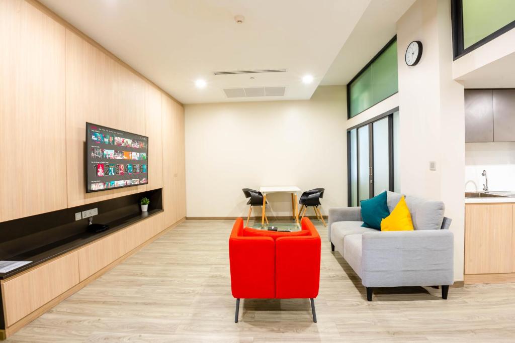 A bright hotel lounge with sofas, a television and a small dining table.