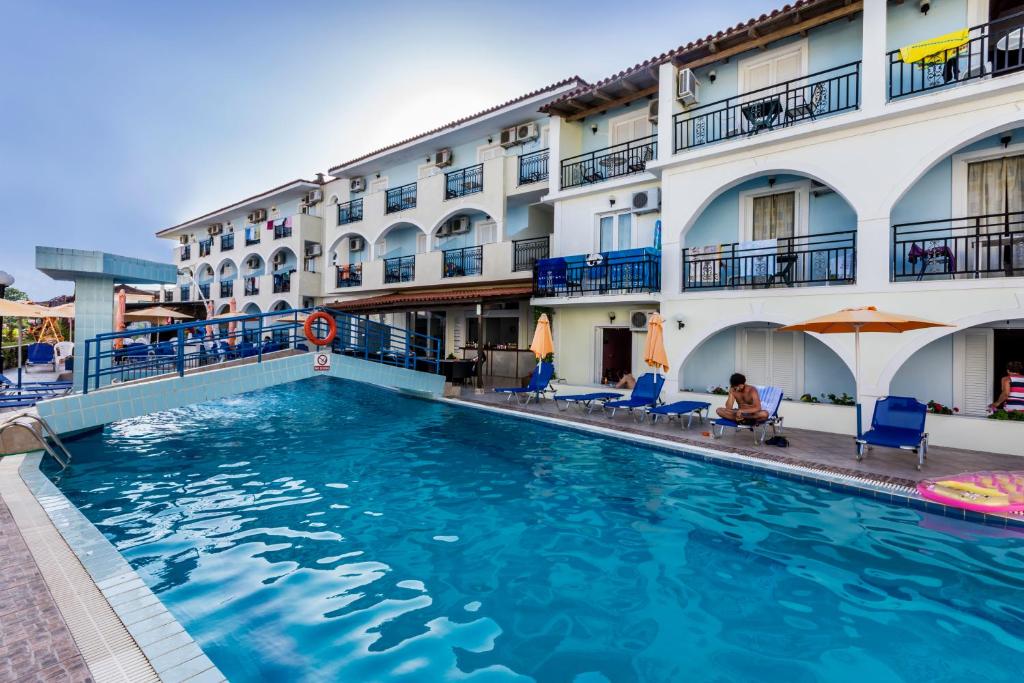 a swimming pool in front of a hotel at Vossos Hotel Apartments in Laganas