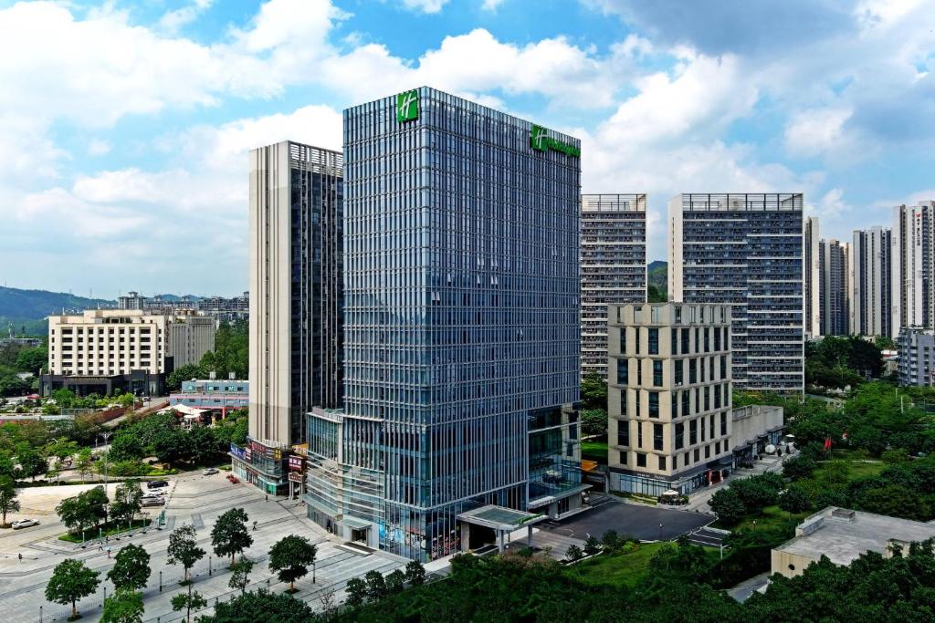 a tall glass building in a city with buildings at Holiday Inn Guangzhou South Lake-an lHG Hotel in Guangzhou