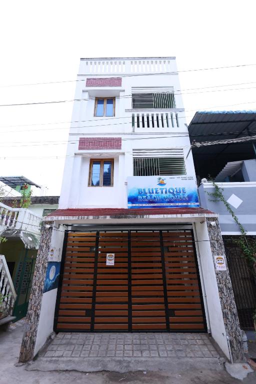 a white building with a large wooden garage door at Bluetique Beach House in Kuilapayam