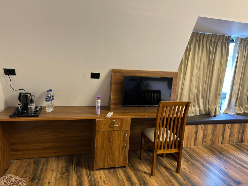 ein Schreibtisch mit einem Fernseher und einem Stuhl in einem Zimmer in der Unterkunft Mangalath River View Resorts in Kodanad