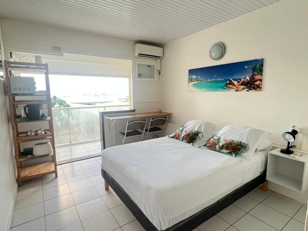 a bedroom with a bed and a view of the ocean at Les Trois Ilets Location Studio Face a la Mer in Les Trois-Îlets