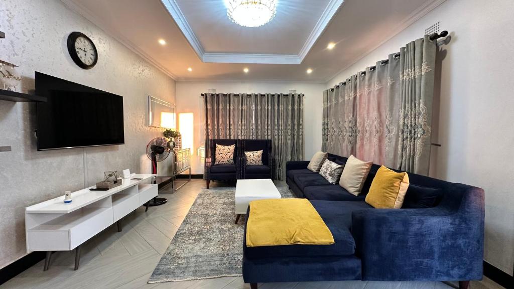 a living room with a blue couch and a tv at Beauty Blender Homes - The Executive House in Lilongwe