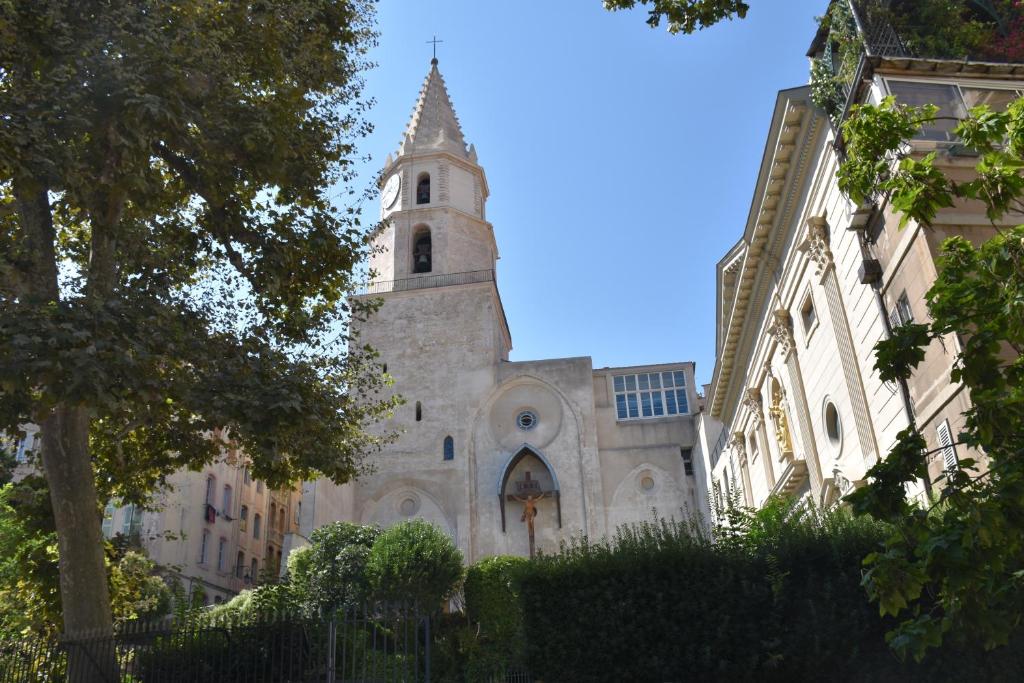 an old church with a steeple and a building at Sous le Clocher in Marseille
