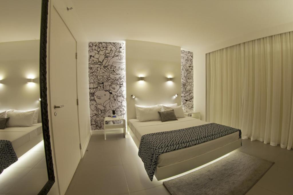 a white bedroom with a bed and a mirror at ibis Styles Maracanau in Maracanaú